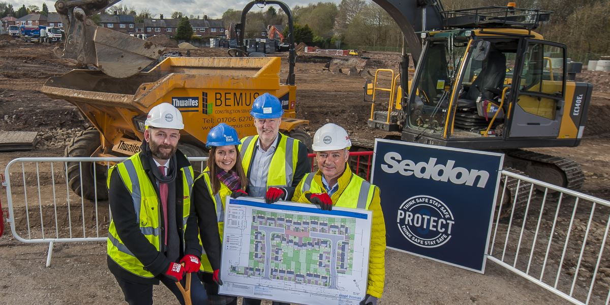 Salford City Mayor, Paul Dennett and others on a building site holding a plan of the new homes